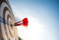 Close up shot red darts arrows in the target center on dark blue sky background. Business target or goal success and winner concept.