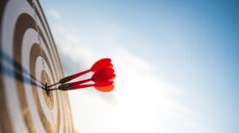 Close up shot red darts arrows in the target center on dark blue sky background. Business target or goal success and winner concept.