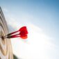 Close up shot red darts arrows in the target center on dark blue sky background. Business target or goal success and winner concept.