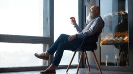 male wine expert tasting wine while sitting in a chair.