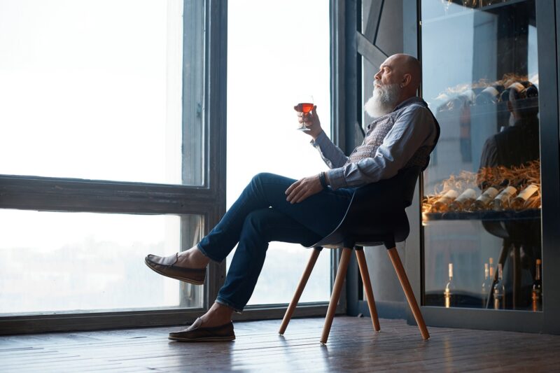 male wine expert tasting wine while sitting in a chair.