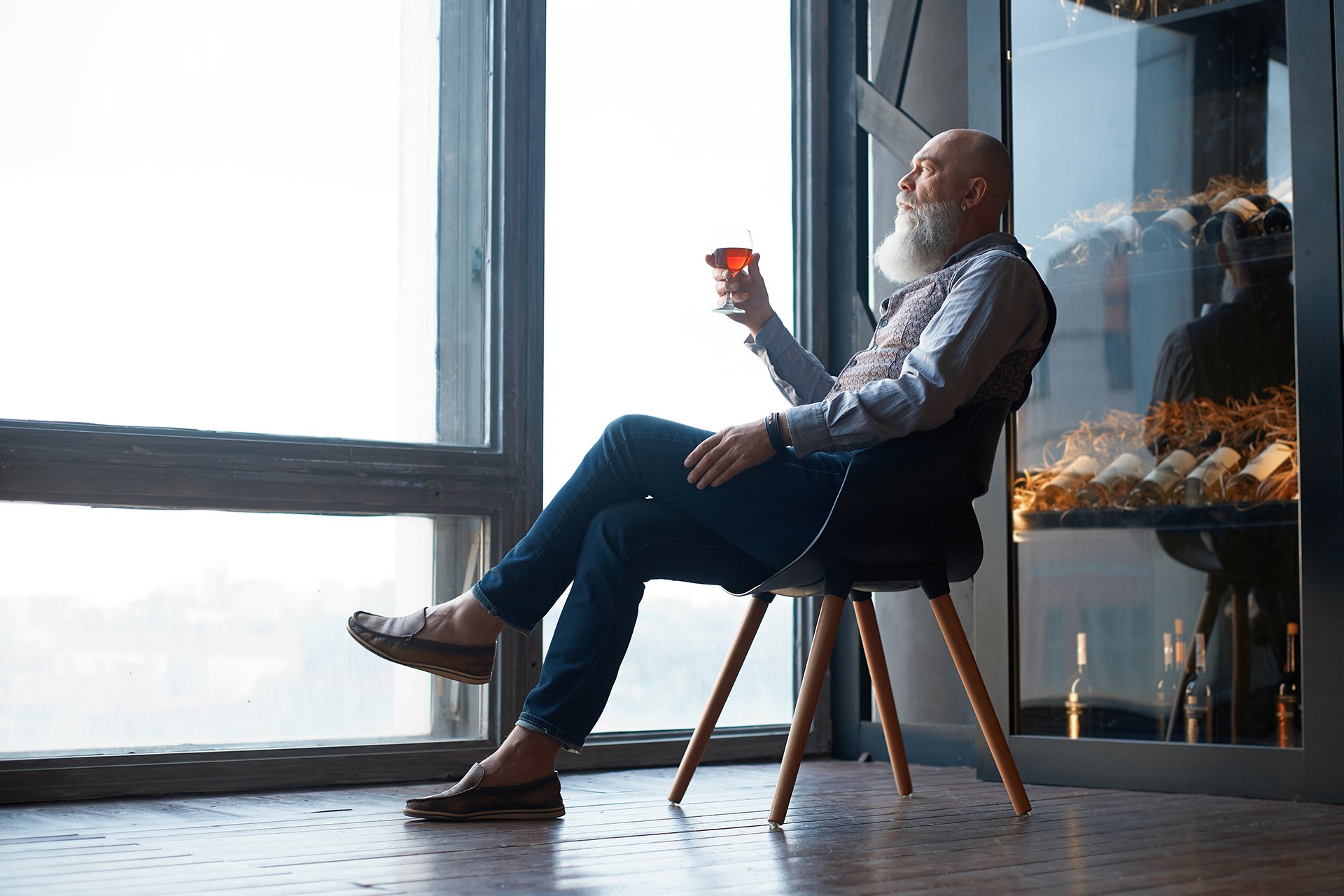 male wine expert tasting wine while sitting in a chair.