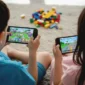 Ilustrasi anak bermain gim daring di ponsel, mencerminkan kontroversi larangan Roblox oleh pemerintah.