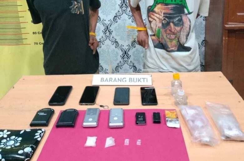 Dua tersangka pengedar sabu berdiri di belakang barang bukti yang disita petugas Satresnarkoba Polres Pariaman usai penggerebekan di kawasan Ladang Rimbo.