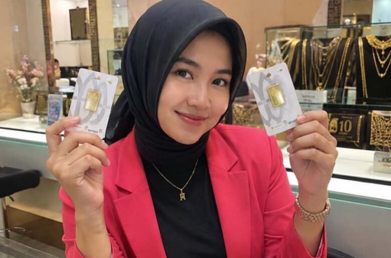 Ilustrasi - Karyawan toko emas memperlihatkan emas mini batangan.