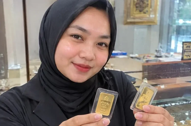 Karyawan toko emas memperlihatkan emas mini batangan.